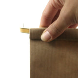 Mano che chiude con busta di carta color avana con laccetto metallico 