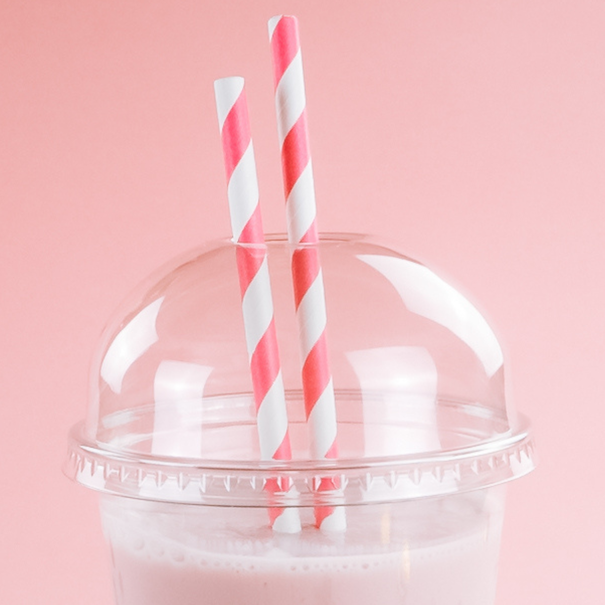 Dettaglio su due cannucce bianche e rosa dentro bicchiere da asporto in plastica con coperchio a cupola