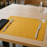 Tovaglietta americana color paglia su tavolino con posate e bicchiere 