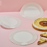 Carta pizzo rotonda, bianca, mostrata stesa e leggermente piegata accanto a torta e fette di torta