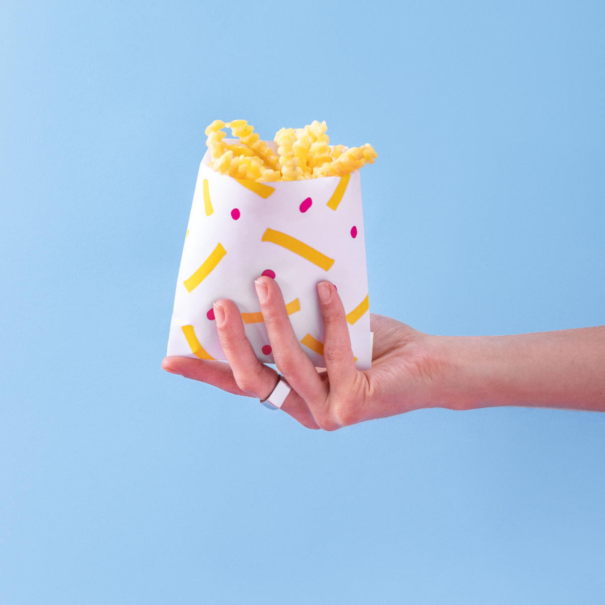 mano che regge sacchettino di carta colorata per patatine, pieno