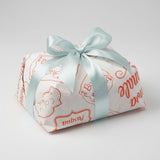 Carta colomba bianca con scritte color arancione di buona Pasqua attorno ad una colomba e nastro azzurro