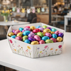 Cesto esagonale con fantasia primaverile pieno di ovetti di cioccolata in carta colorata 