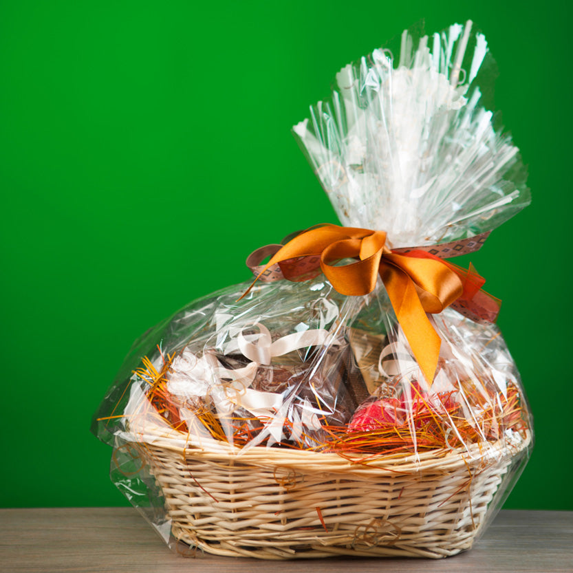 Cesto natalizio di vimini ricoperto di cellophane pieno di prodotti 