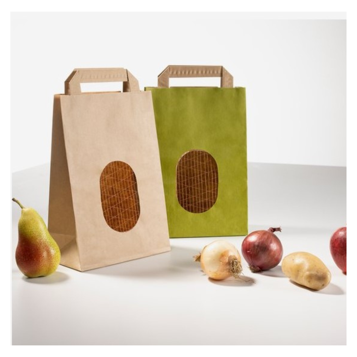 Shopper di carta con finestra e rete una avana ed una verde accanto pere, cipolle e patate 