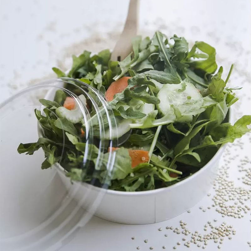 Ciotola di carta, bianca, con coperchio di plastica, su tavolino, piena di insalata 