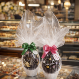 Due uova di pasqua avvolte dal cellophane una con fiocco verde ed una con fiocco rosa sulla vetrina di un bar 