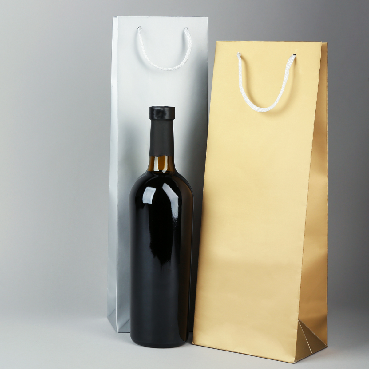 Buste per vino, color oro e color argento e bottiglia di vino