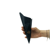 Mano che regge un cono di carta nero con una rosa dorata stampata, vuoto 