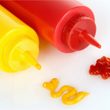 Dettaglio di due dosatori per salse, uno giallo ed uno rosso, con delle salse 