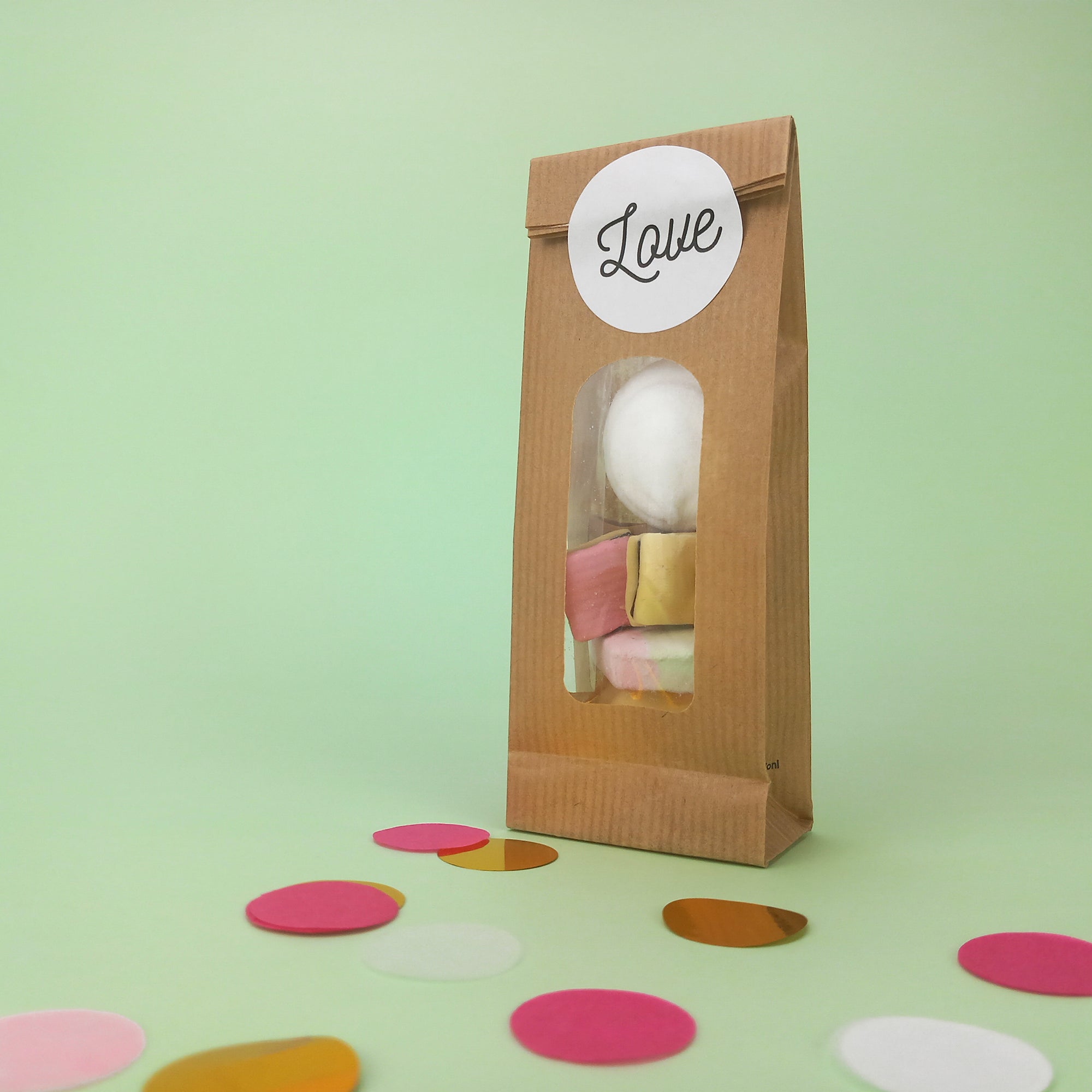 Etichetta tonda adesiva LOVE attaccata ad un sacchetto di carta color avana con finestra pieno di caramelle gommose 