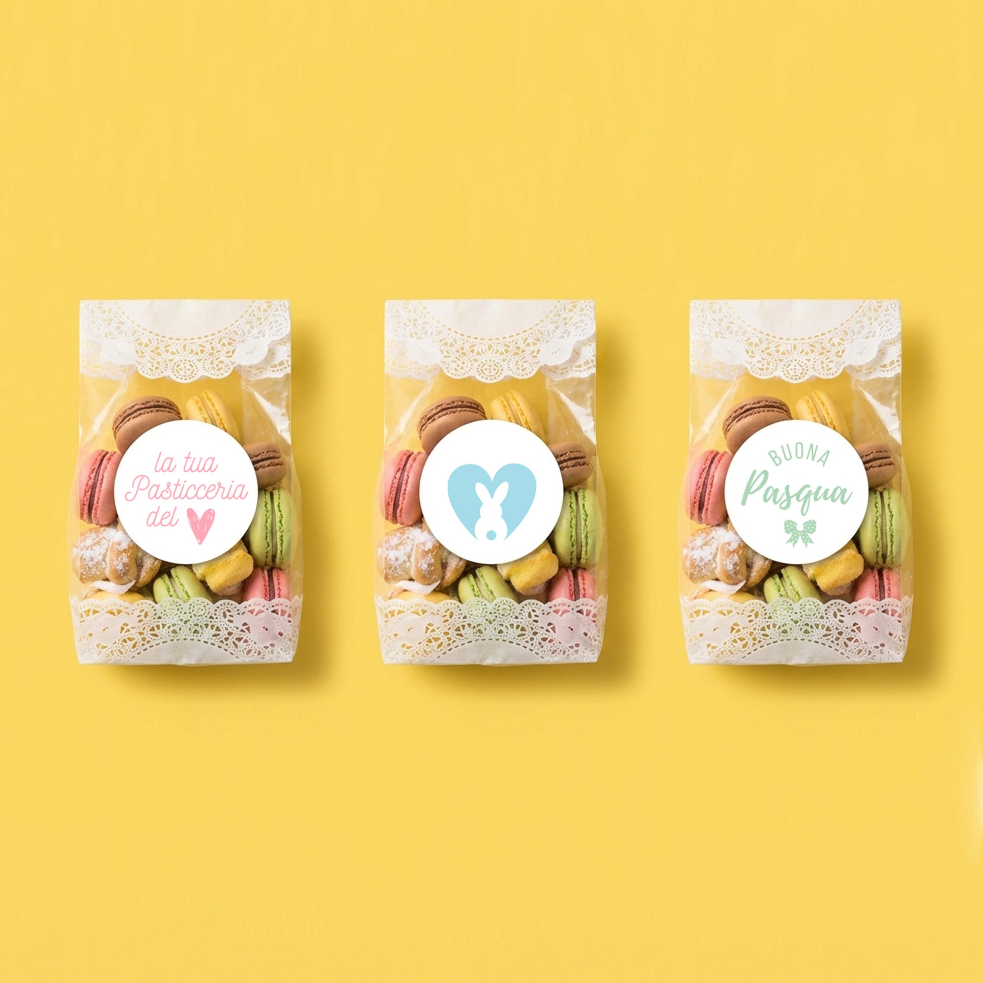 Tre sacchetti trasparenti pieni di macarons e dolci con attaccato tre etichette tonde pasquali 