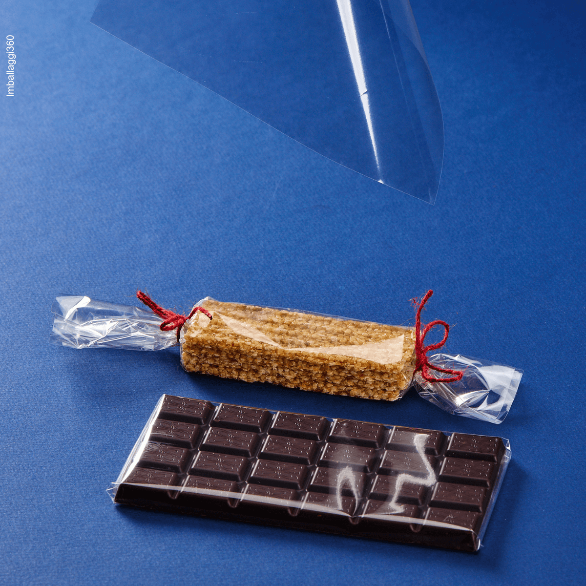 Foglio trasparente per alimenti che avvolgono tavolette di cioccolato e dettaglio di un foglio. Sfondo blu