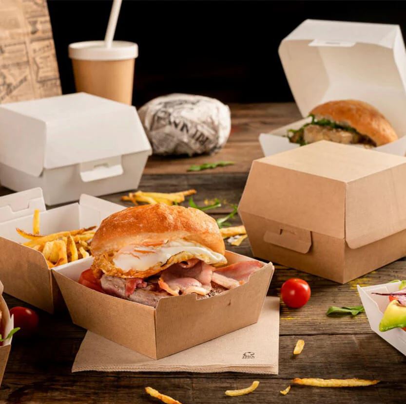 Scatole avana porta hamburger su tavolo di legno, piene, alcune aperte ed altre chiuse assieme a patatine sparse 