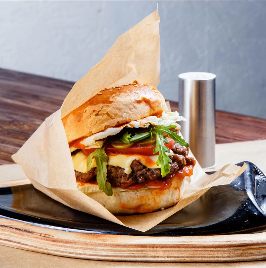 Hamburger avvolto da carta antigrasso su un tavolo
