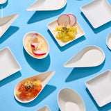Monoporzioni per fingerfood alcune vuote altre piene di cibo disposte su sfondo azzurro