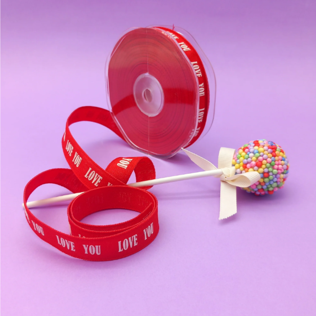Nastro rosso con scritta love you con lollipop vicino, sfondo violetto