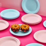 Piatti bio monouso color rosa e azzurro. In primo piano un piatto azzurro con due dolci