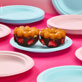 Piatti bio monouso color rosa e azzurro. In primo piano un piatto azzurro con due dolci