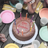 Torta cioccolato Happy Birthday con candeline accese su tavolo di lego e bambini attorno
