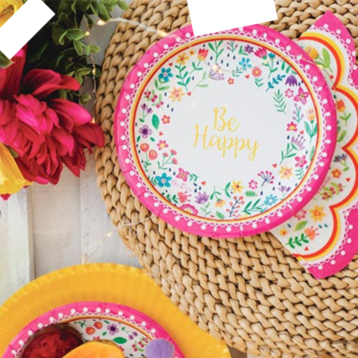 Piatto di carta monouso fantasia Be Happy su tavola imbandita e fiori