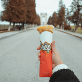 Mano che regge un porta crepes di carta pieno 