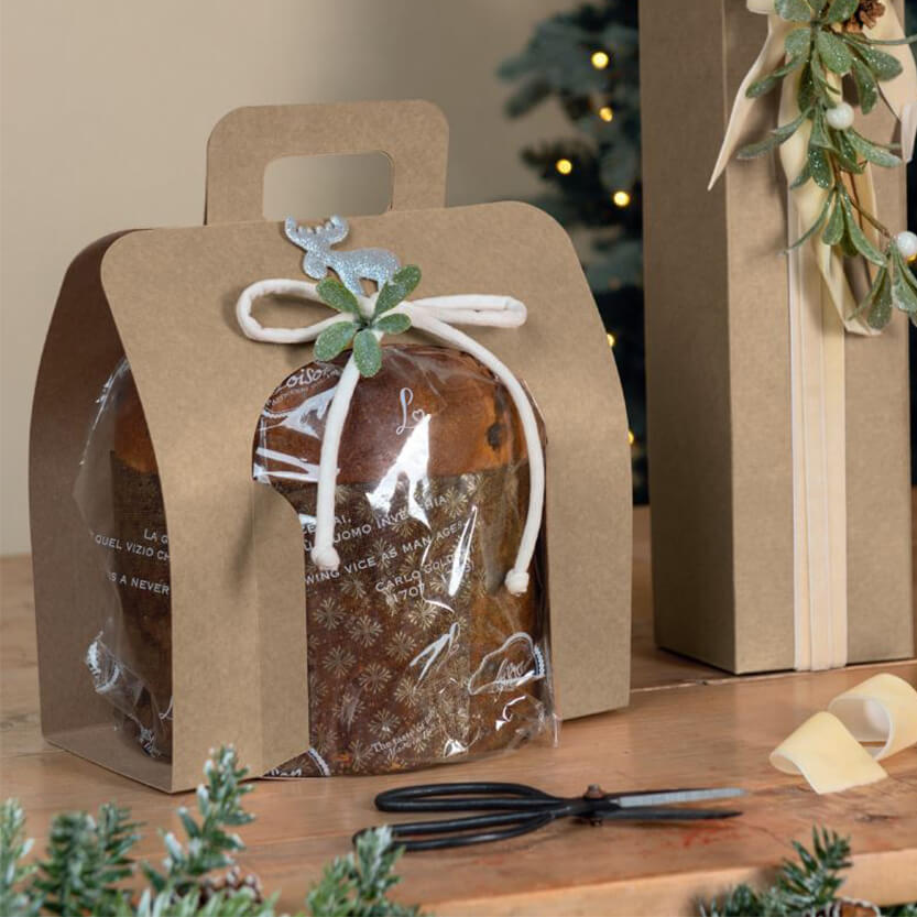Porta panettone color avana aperto ai lati con dentro un panettone, su una tavola accanto altro pacco 