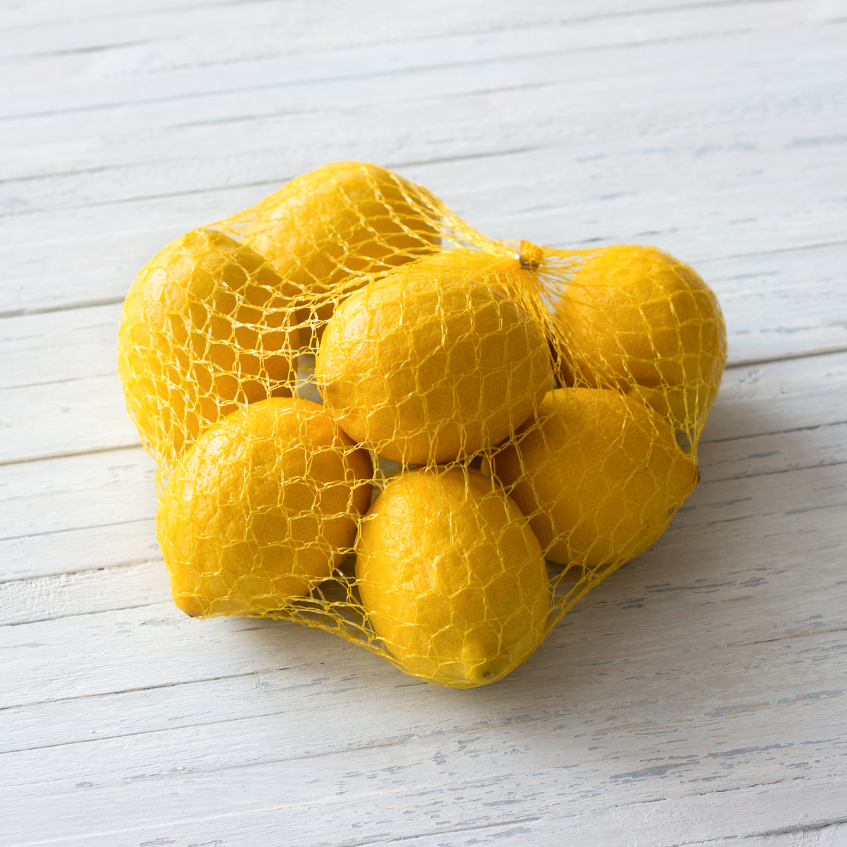 Rete per limoni, gialla, piena di limoni su tavolino