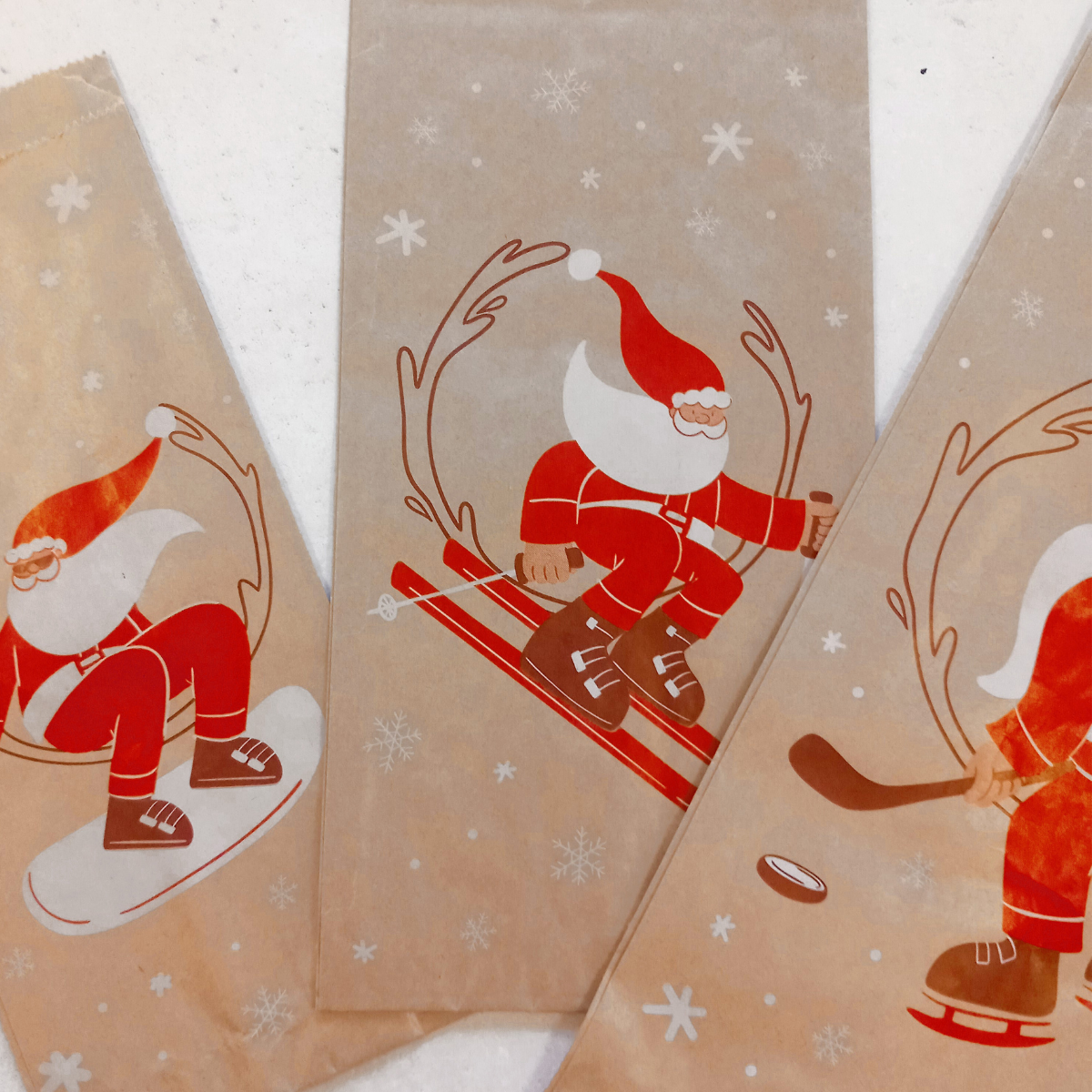 Tre sacchetti di carta color avana con simboli natalizi 