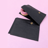 Sacchetti, due, di carta neri, uno vuoto ed uno con una donut rosa 