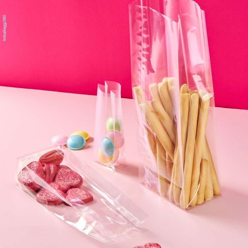 Sacchetto trasparenti a fondo quadro, ripieni di dolci e grissini, varie misure, su sfondo rosa