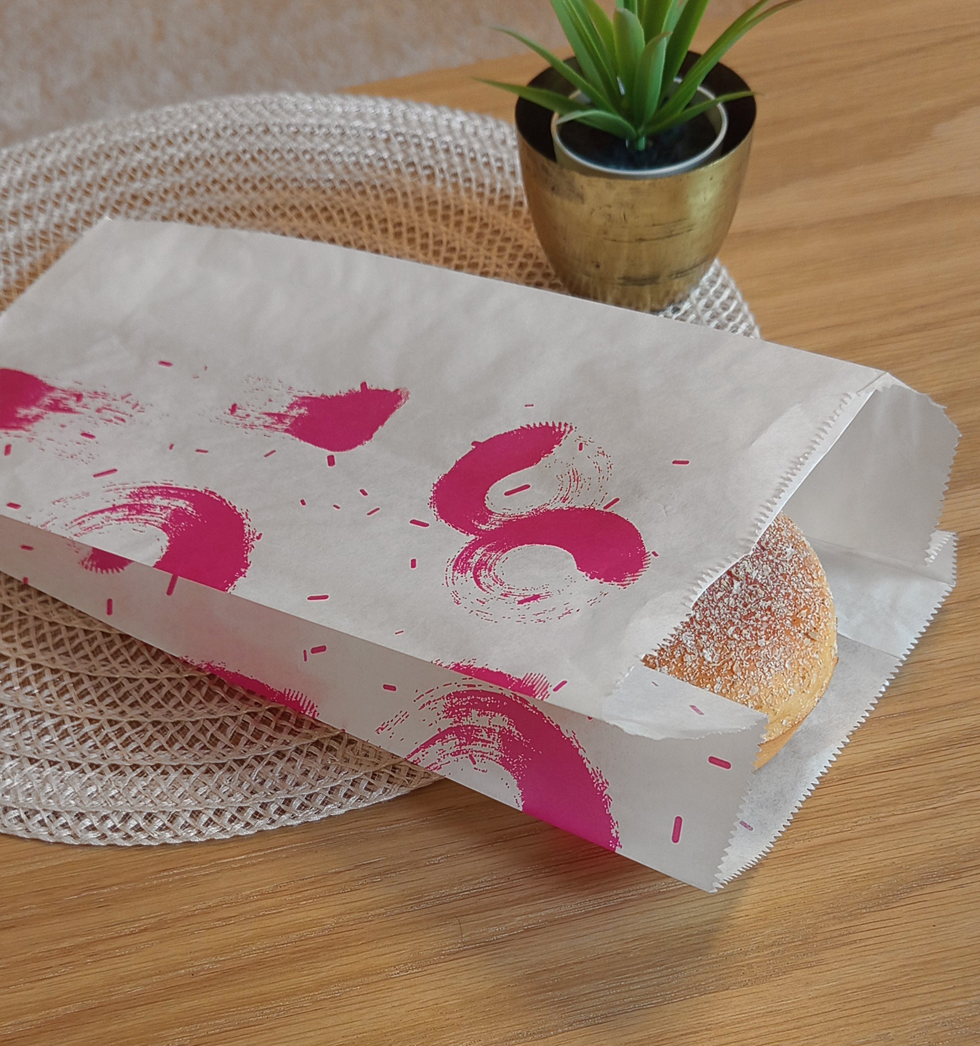 Sacchetto bianco per il pane con macchie di colore viola, su un tavolo con dentro  un panino