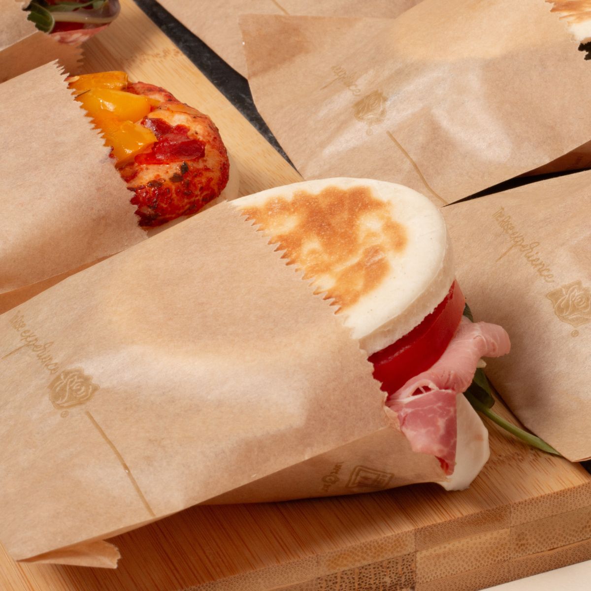 Sacchetti antigrasso color avana, su un tavolo, ripieni di panini