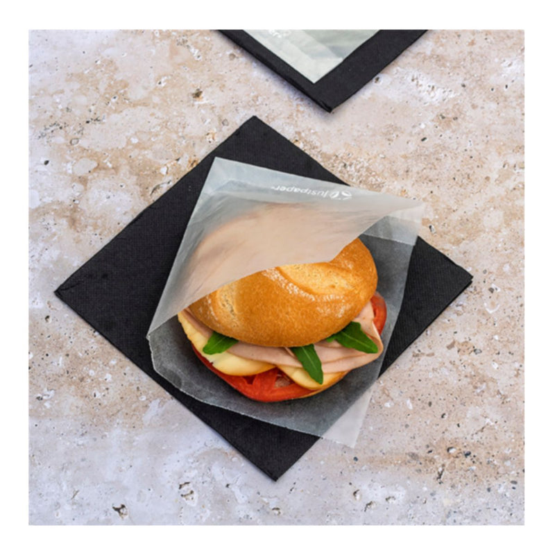 Sacchetto antigrasso trasparente opaco, aperto da due lati con dentro un panino, su un fazzoletto nero