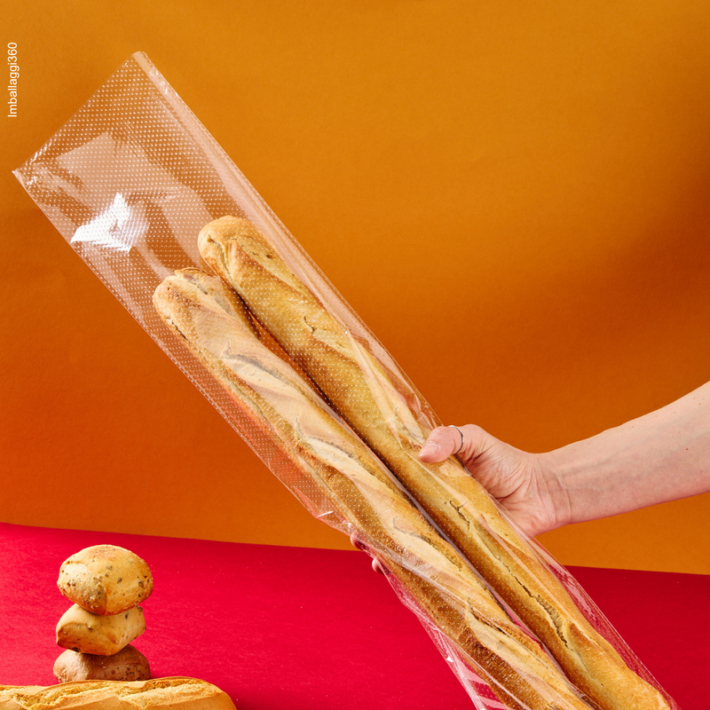 Sacchetto microforato , mostrato con del pane, dentro, retto da una mano. Sfondo rosso
