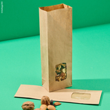 Sacchetto color avana di carta con finestra porta alimenti, mostrato con cibo all'interno ma anche vuoto steso, su sfondo verde