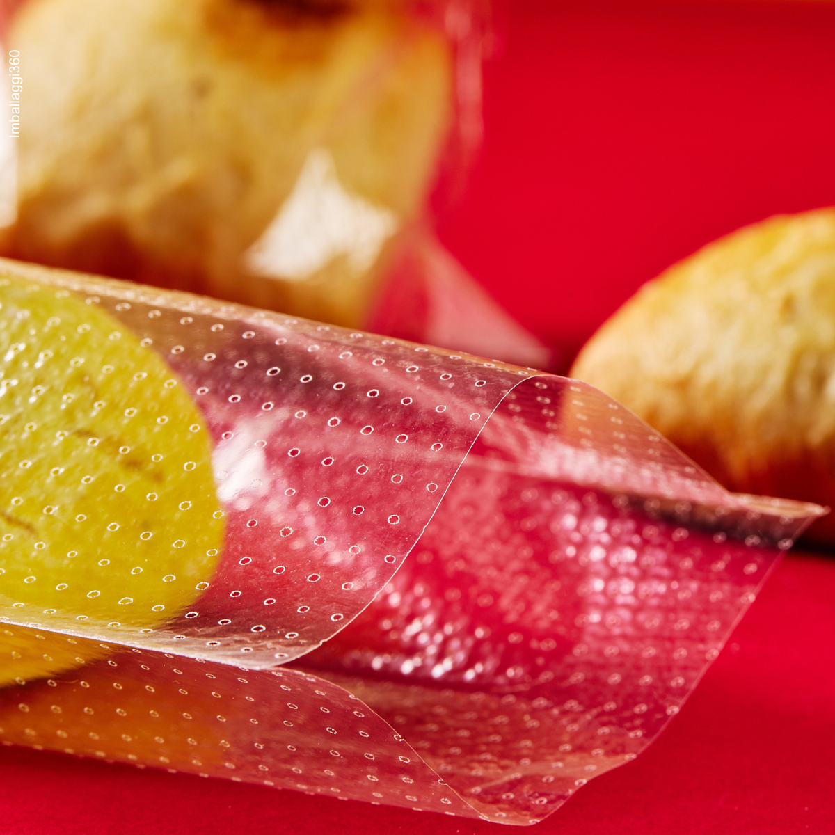 Sacchetto microforato , mostrato con del pane, dentro, anche steso. Dettaglio. Sfondo rosso