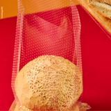 Sacchetto microforato , mostrato con del pane, dentro, dettaglio. Sfondo rosso