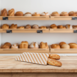 Panificio con in primo piano busta del pane a righe con due filoni dentro 