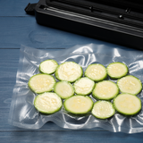 Sacchetto sottovuoto ripieno di zucchine a fette, su un tavolo, vicino alla macchina crea sottovuoto