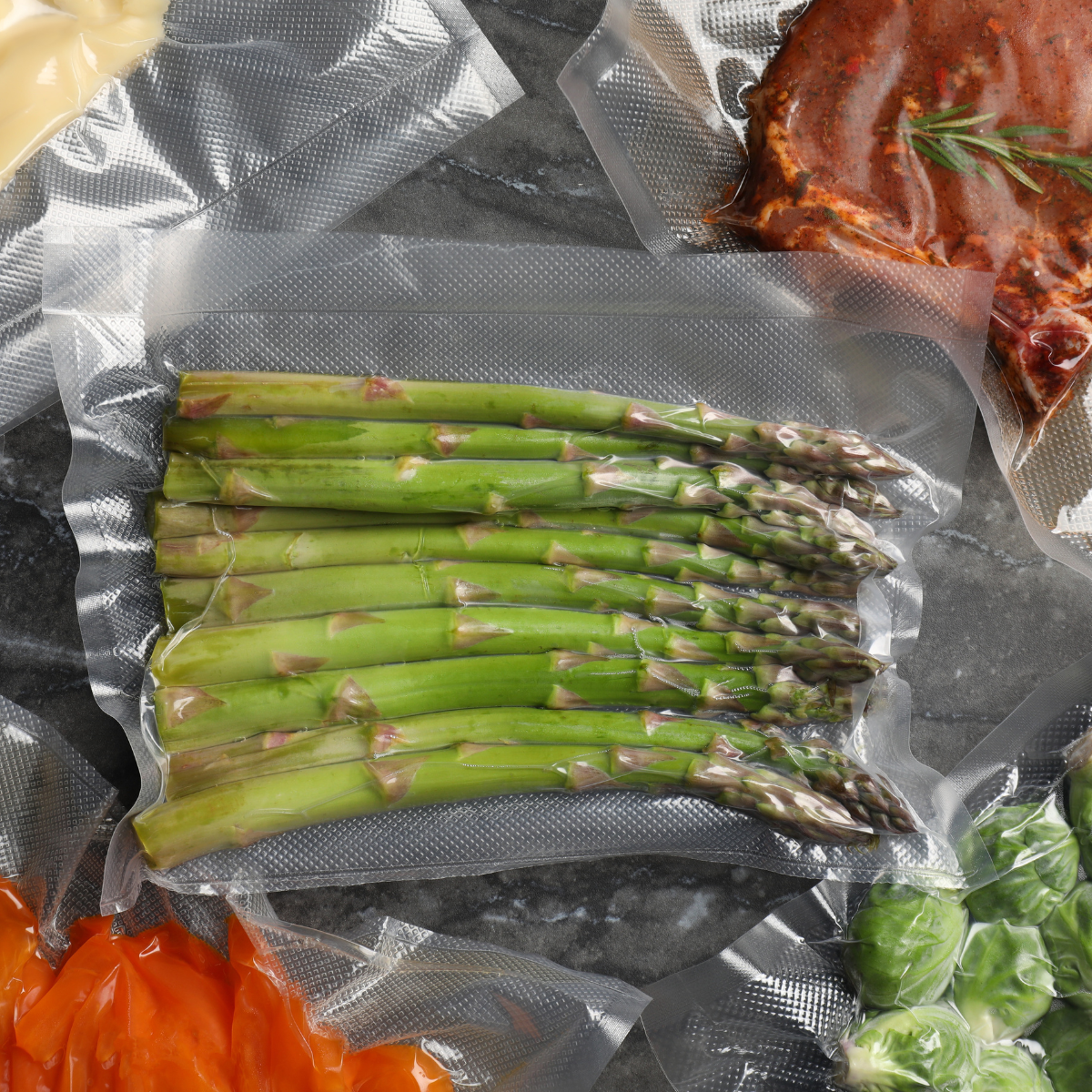 Sacchetto sottovuoto, con asparagi all'interno, chiuso tra altri sacchetti contenenti altro cibo, su un tavolo