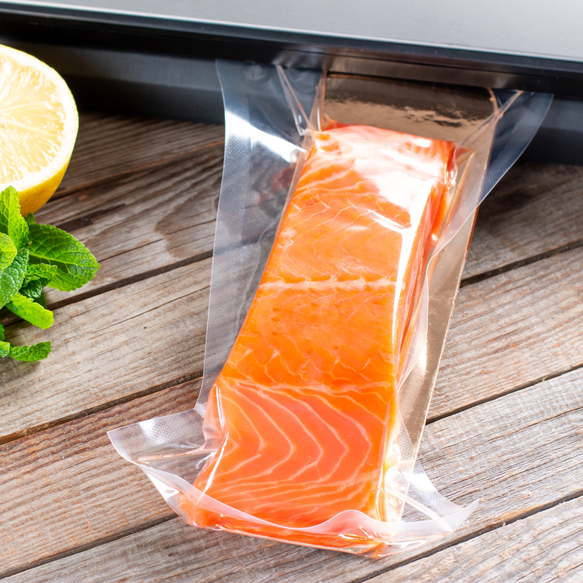 Sacchetto sottovuoto vicino alla sua macchina, con dentro salmone su un tavolino 