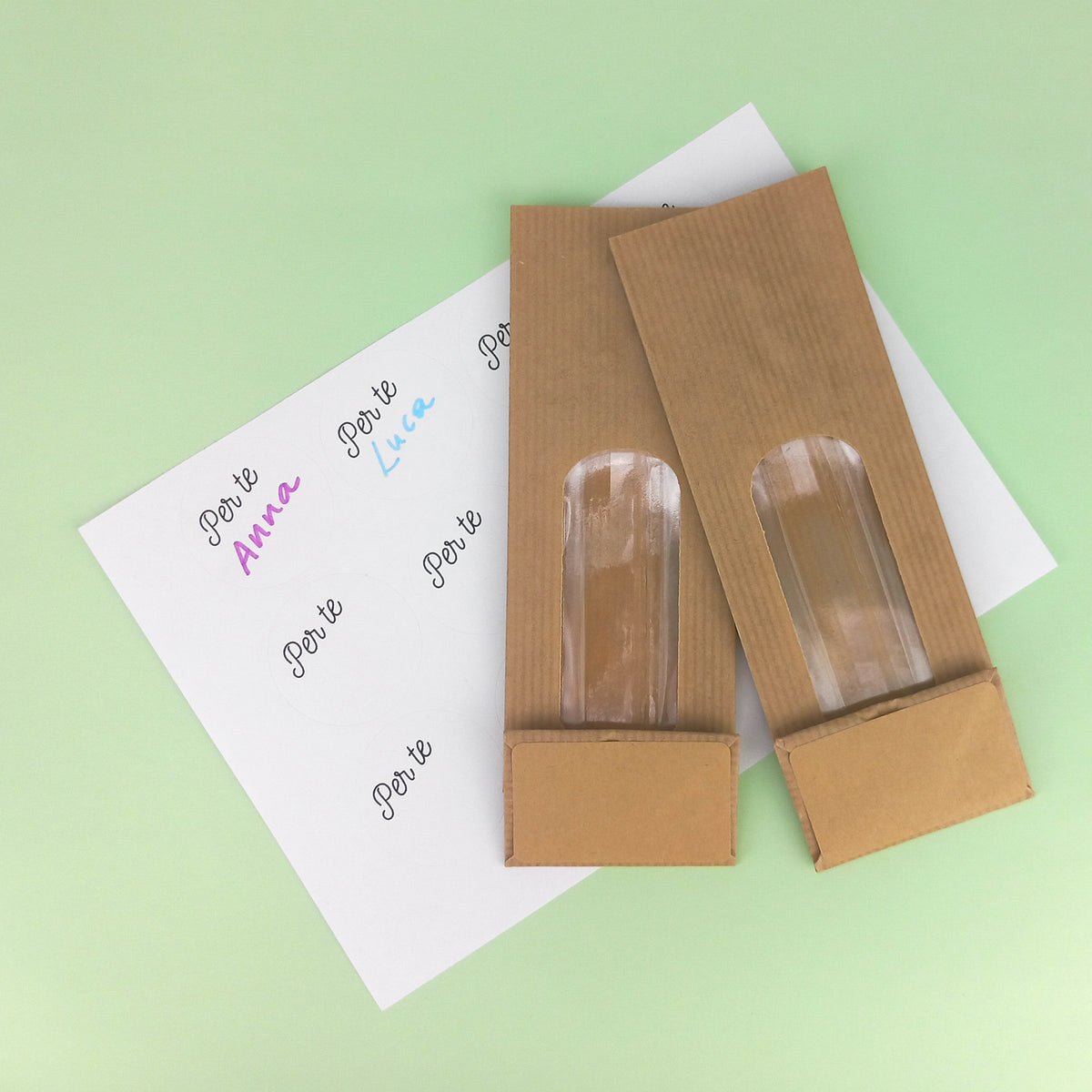 Due sacchetti quadrati di carta color avana con finestra, stesi su carta bianca Per te
