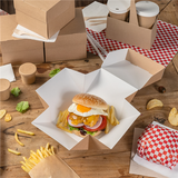 Scatola per hamburger aperta su un tavolino, tra altre con un panino dentro