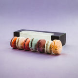 Scatola nera di cartone porta macarons e alcuni macarons colorati