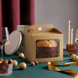 Scatola color avana con finestra con dentro panettone su una tavola verde