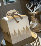 Scatola panettone bianca con fantasia foresta su un tavolino sullo sfondo elementi di decorazioni natalizie 
