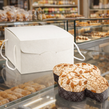 Scatola porta colomba bianca sulla vetrina di una pasticceria con vicino una colomba 
