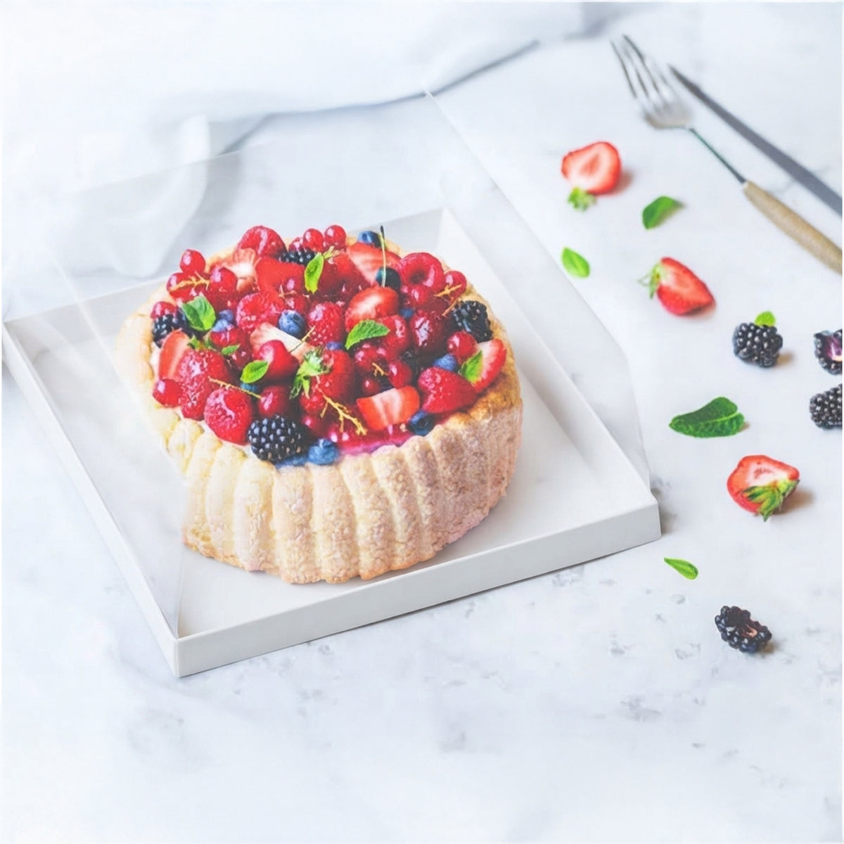 Scatola porta torte quadrata, mostrata con base bianca e dentro una torta ai frutti di bosco