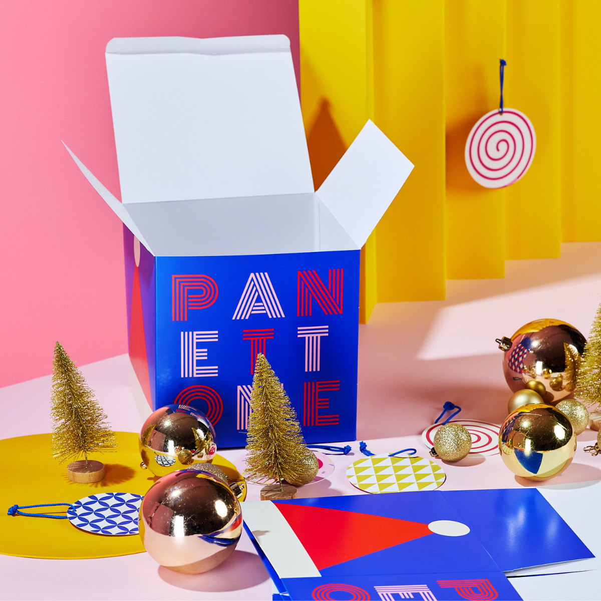 Scatola panettone circus aperta tra palline dorate alberelli  palline di natale